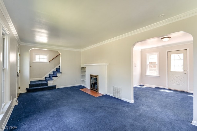 unfurnished living room featuring carpet floors, stairs, arched walkways, and ornamental molding