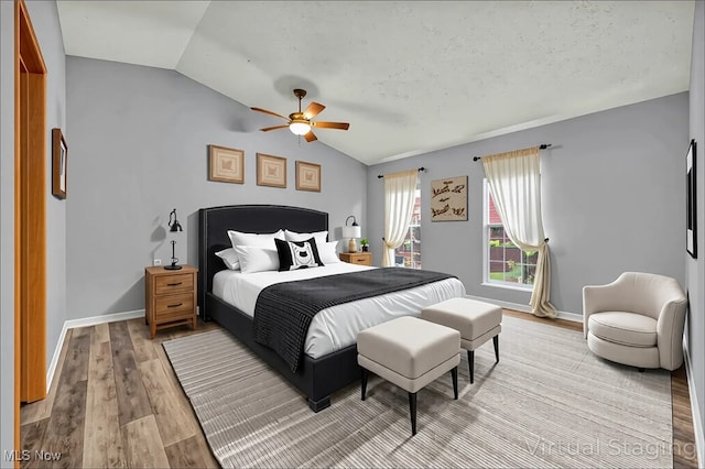 bedroom featuring light wood finished floors, lofted ceiling, baseboards, and ceiling fan