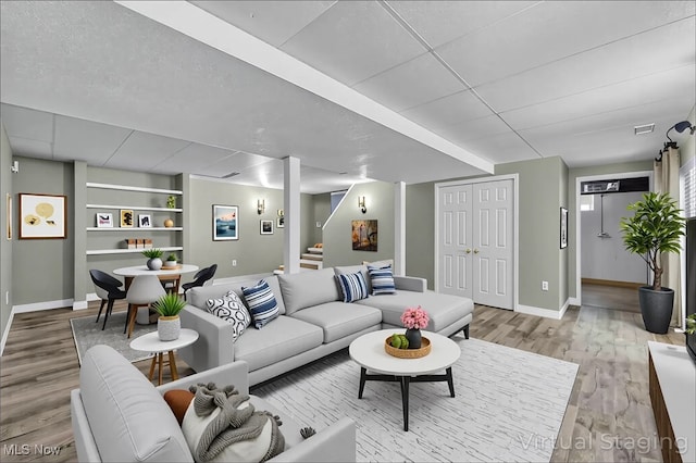 living area featuring baseboards, stairway, built in features, and wood finished floors