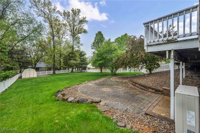 view of yard with an outbuilding, a shed, a fenced backyard, and a patio