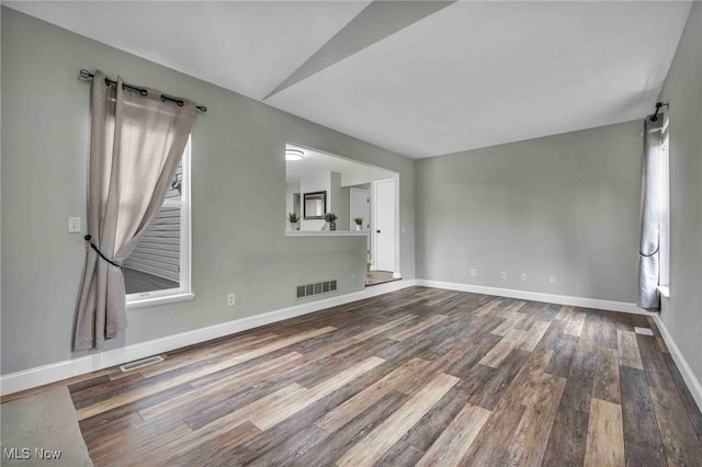 unfurnished living room featuring visible vents, wood finished floors, and baseboards