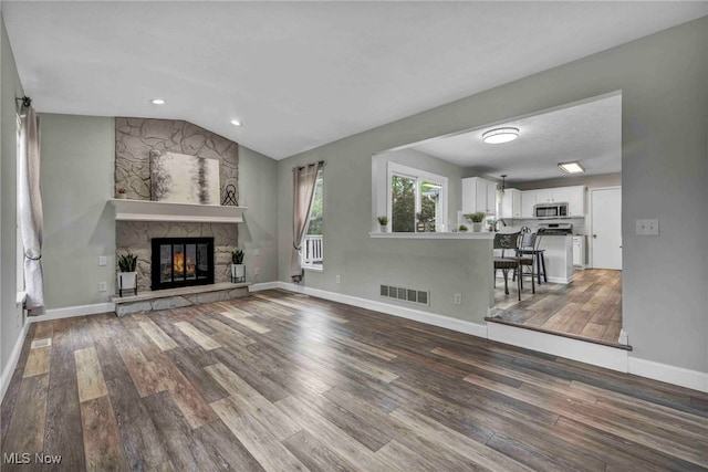 unfurnished living room with baseboards, visible vents, wood finished floors, and a fireplace