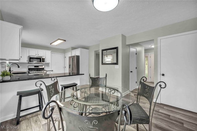 dining area featuring light wood-style floors and a textured ceiling