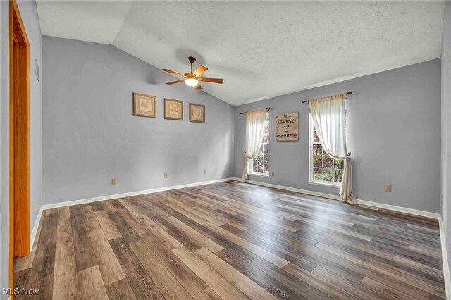unfurnished room with a ceiling fan, wood finished floors, vaulted ceiling, a textured ceiling, and baseboards