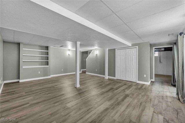 basement featuring built in features, wood finished floors, and baseboards