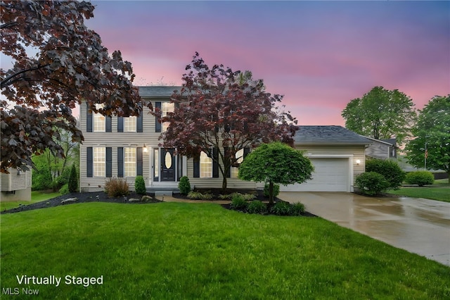 colonial-style house featuring a lawn, driveway, and a garage