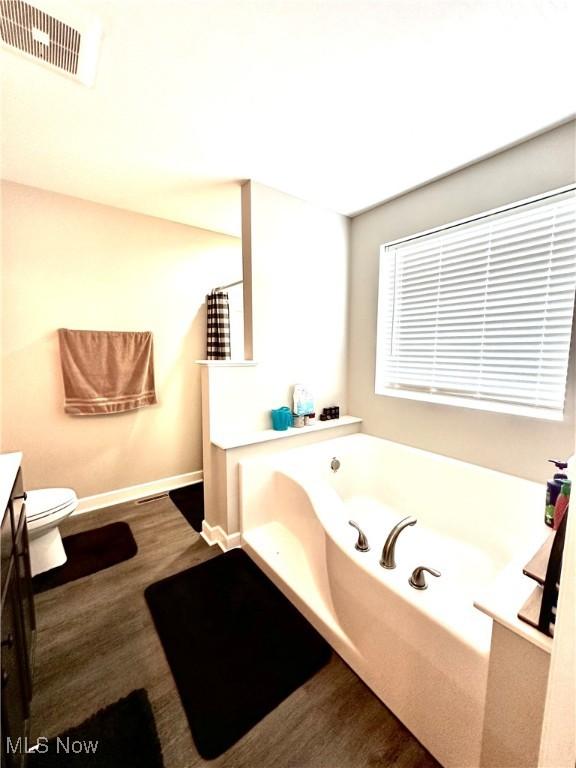 11149 Rankin Rd, Glenford, OH 43739 - full bath with vanity, wood finished floors, a garden tub, baseboards, and toilet