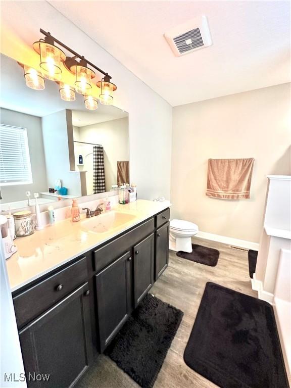 11149 Rankin Rd, Glenford, OH 43739 - bathroom with vanity, wood finished floors, toilet, a shower with shower curtain, and baseboards