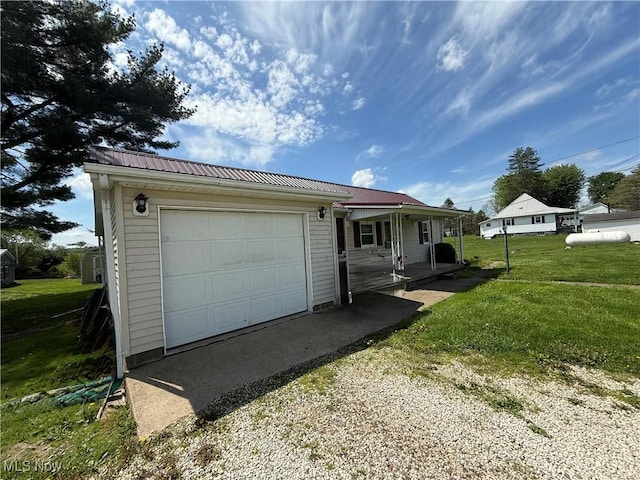 single story home with a front lawn, metal roof, covered porch, and a garage