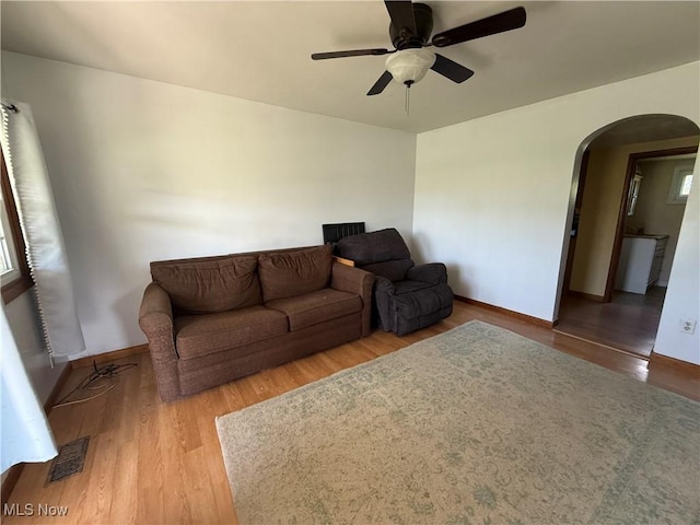 living area with baseboards, ceiling fan, visible vents, wood finished floors, and arched walkways