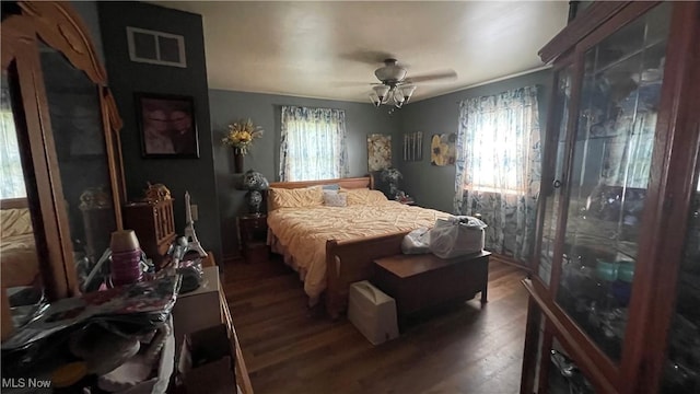 bedroom featuring ceiling fan, multiple windows, visible vents, and wood finished floors