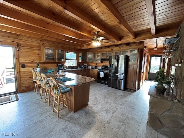165 Township Rd Unit 1461, Greenwich, OH 44805 - kitchen with black gas stove, wooden walls, a wealth of natural light, and stainless steel refrigerator with ice dispenser