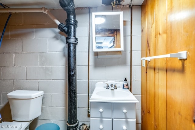 396 2nd St NE, Carrollton, OH 44615 - bathroom featuring concrete block wall, vanity, and toilet