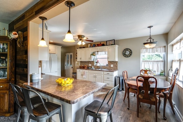 396 2nd St NE, Carrollton, OH 44615 - kitchen featuring freestanding refrigerator, a sink, a peninsula, dark wood-style flooring, and a ceiling fan