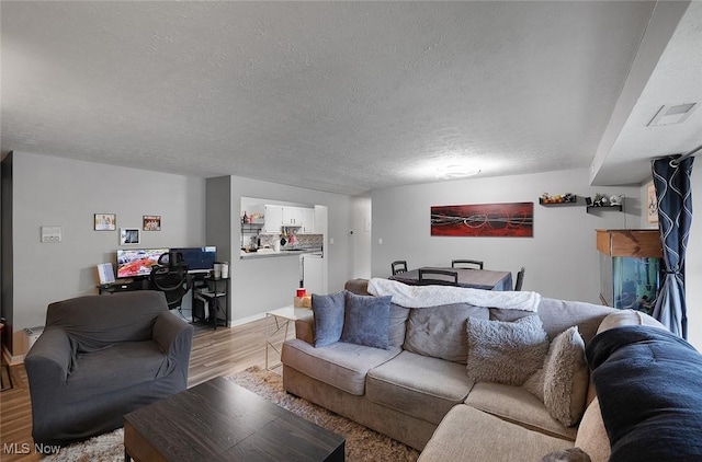 living room featuring light wood finished floors, a textured ceiling, and baseboards