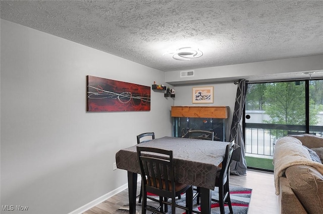 dining space with wood finished floors, baseboards, and a textured ceiling