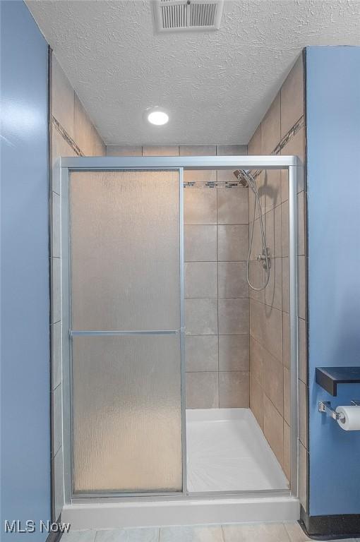 bathroom with a stall shower and a textured ceiling