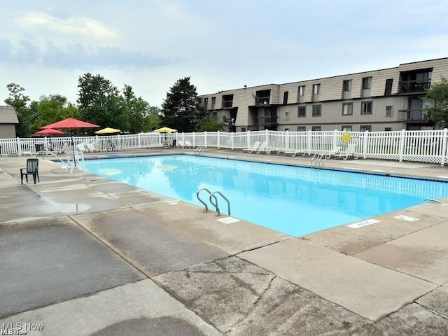community pool with fence and a patio