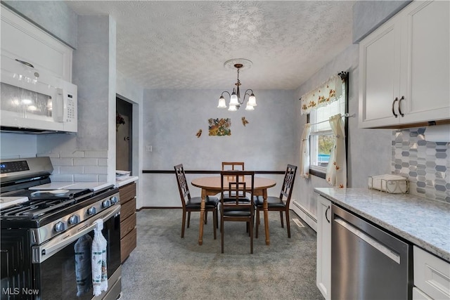 kitchen with stainless steel appliances, tasteful backsplash, a chandelier, light carpet, and a textured ceiling