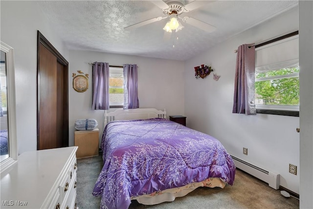 bedroom with baseboard heating, carpet, multiple windows, a closet, and a textured ceiling
