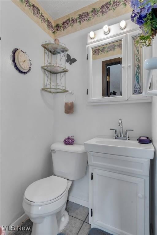 bathroom featuring baseboards, toilet, vanity, and tile patterned floors