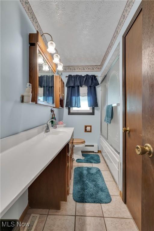 full bath featuring a baseboard heating unit, toilet, a textured ceiling, vanity, and shower / bath combination with glass door