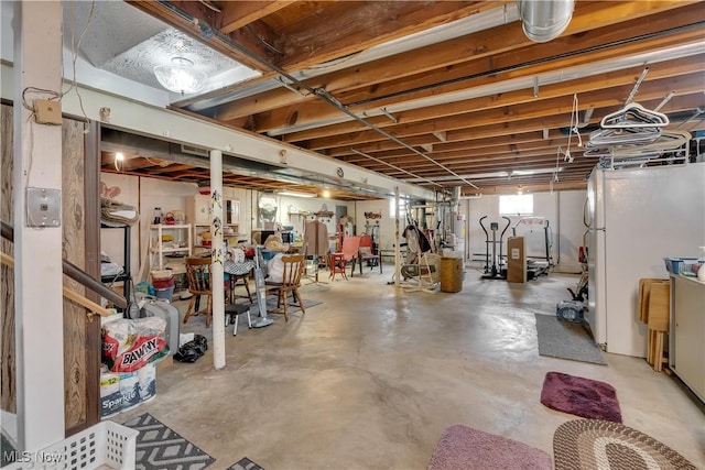 below grade area featuring water heater and freestanding refrigerator