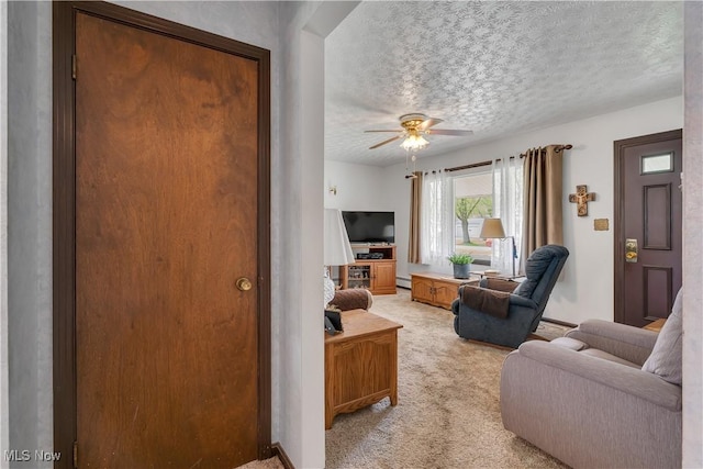 living area with a textured ceiling, light carpet, a baseboard heating unit, and a ceiling fan