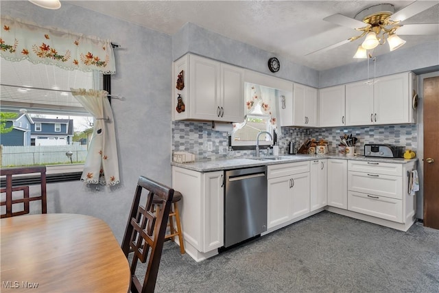kitchen featuring stainless steel dishwasher, a sink, tasteful backsplash, and white cabinetry