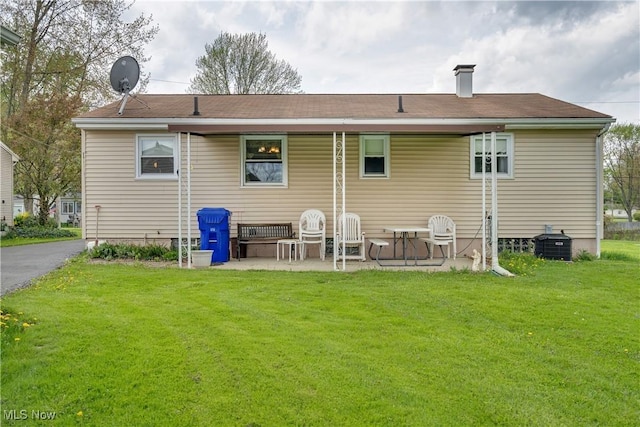back of house featuring a yard, a patio area, and a chimney
