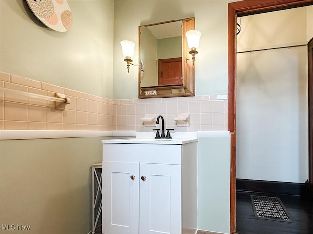 bathroom with tile walls, vanity, and a wainscoted wall