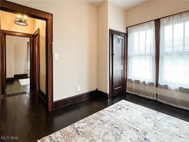 foyer featuring dark wood-style flooring, baseboards, and a chandelier