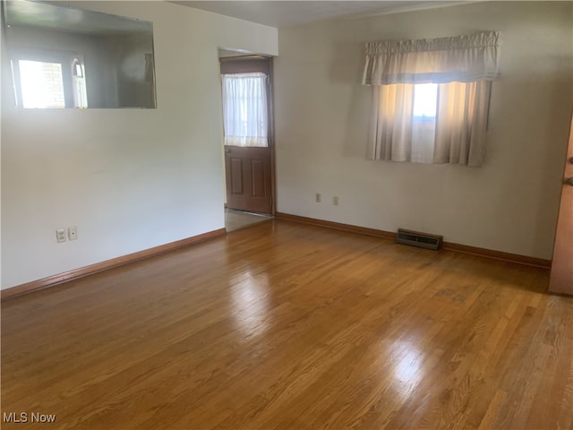 empty room with plenty of natural light, wood finished floors, and baseboards