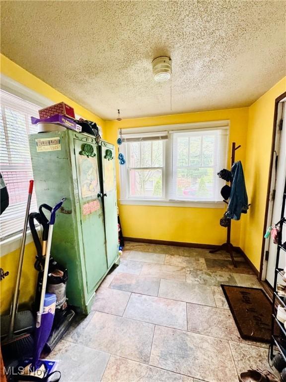 741 Jennings Ave, Salem, OH 44460 - exercise area with healthy amount of natural light, baseboards, a textured ceiling, and stone finish floors