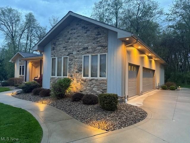 view of home's exterior with stone siding, driveway, and a garage