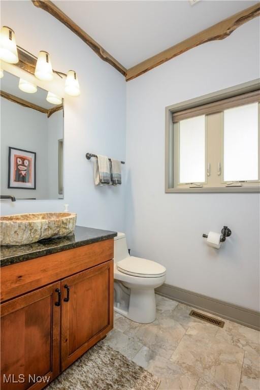 half bath with toilet, vanity, and baseboards