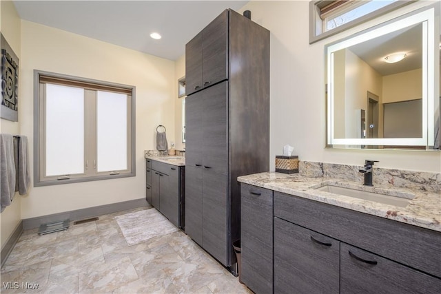 full bath with two vanities and baseboards
