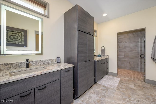bathroom with two vanities, a shower stall, and baseboards