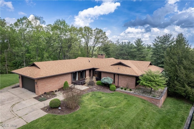 single story home featuring driveway, brick siding, a front yard, and roof with shingles