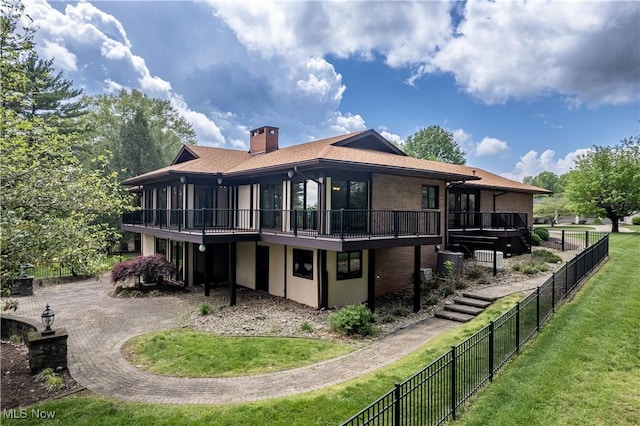 back of property with a chimney, brick siding, cooling unit, and a deck