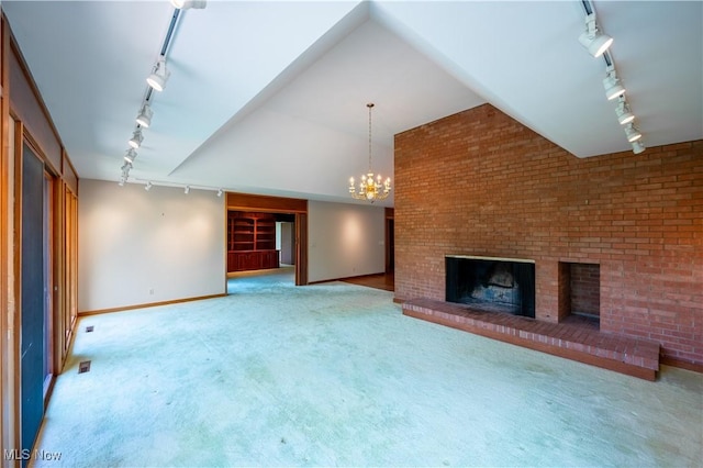 unfurnished living room with rail lighting, a brick fireplace, carpet flooring, and baseboards