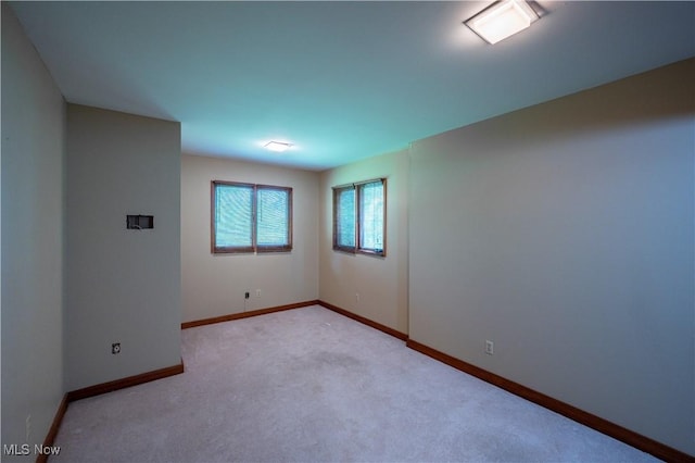 unfurnished room featuring baseboards and light colored carpet