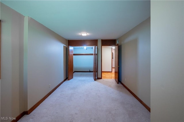 hall with light colored carpet and baseboards