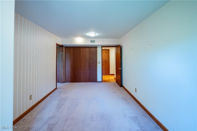 unfurnished bedroom featuring baseboards, light colored carpet, and a closet