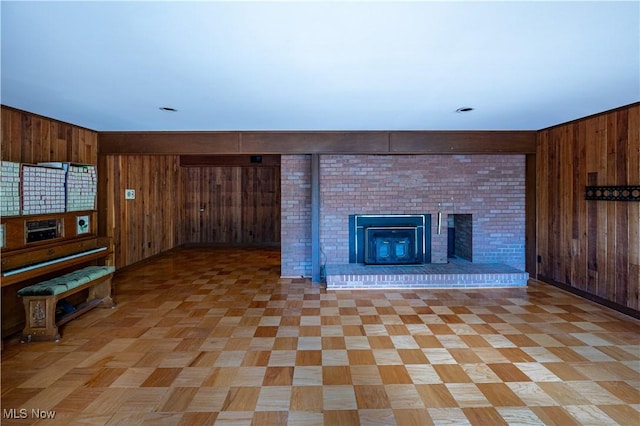 unfurnished living room featuring wooden walls and a fireplace