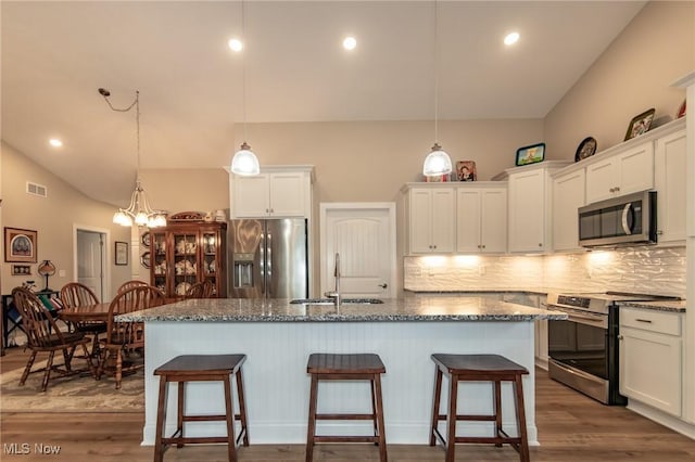 kitchen with stainless steel appliances, a sink, lofted ceiling, backsplash, and white cabinets
