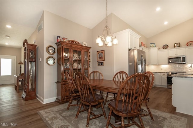dining area featuring lofted ceiling, a chandelier, wood finished floors, baseboards, and recessed lighting
