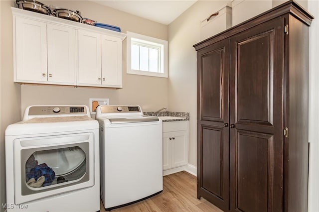 laundry room featuring separate washer and dryer, cabinet space, and light wood finished floors