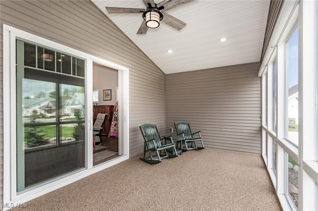 sunroom with carpet floors, vaulted ceiling, ceiling fan, wooden walls, and recessed lighting