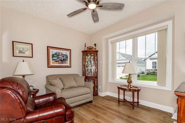 living room with light wood finished floors, ceiling fan, and baseboards